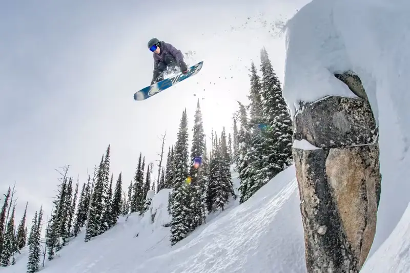 A snowboarder airborne above a snowy ridge at Whitewater Mountain Resort